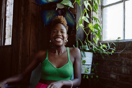 Young Black woman in colorful attire smiles at camera while laughing