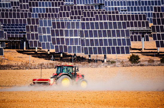 Tractor plowing a field next to a solar panel park in El Bonete