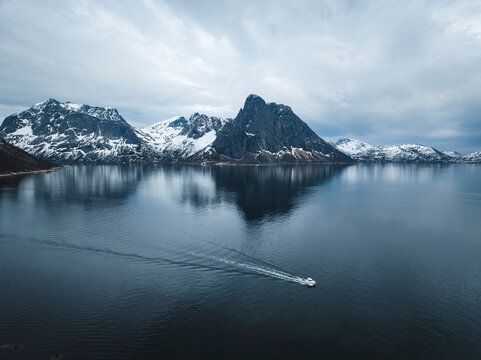 Drone shot of boat in ocean by snow covered mountains against sky