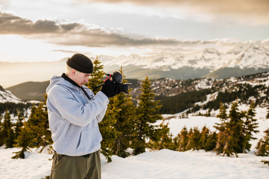 Young man filming snowy mountains