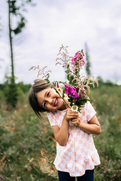 Asian girl smiling with flowers with the sun shining in field