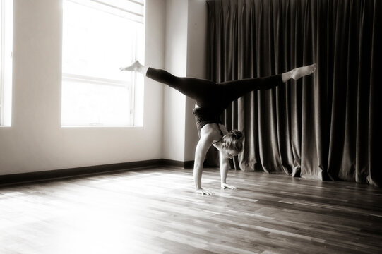 Woman in Handstand Split in front of Curtain