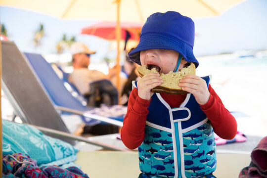 Toddler Boy Wearing Life Jacket Eats PBJ on the Beach