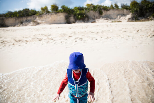 Low Angle Toddler Boy in Life Jacket Plays at Edge of Caribbean Sea