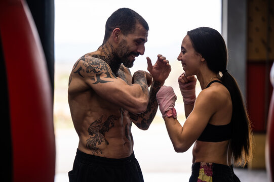Cheerful couple practicing Muai Thai in gym