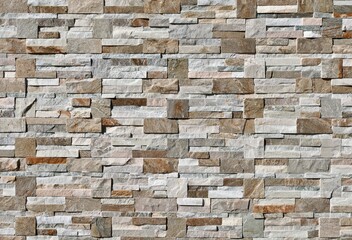 Stone external wall paneling made of bricks and cubes of white,brown and gray rocks. Background and texture.
