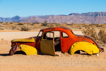 Rustic, weather-beaten cars lie abandoned amidst the stark landscape of Solitaire in Namibia, their...