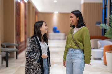 マンションのフロントロビーで３０代の台湾人女性と２０代のアジア人女性が談笑している風景 Scenery of Taiwanese women in their 30s and Asian women in their 20s chatting in the front lobby of the apartment