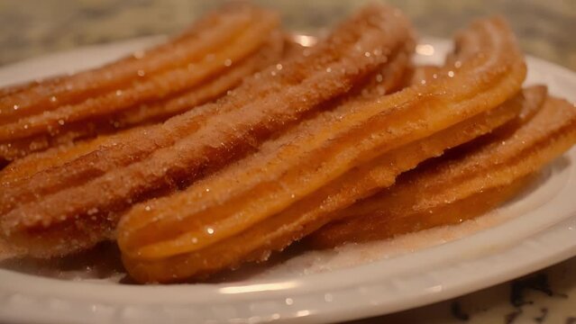 A white plate holding churros covered in sugar.