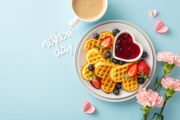Charming Mother's Day table top view arrangement: heart-shaped waffles, strawberries, blueberries, fruit spread, espresso, carnations, 