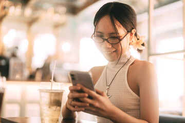 Asian woman gen z in Y2K trendy fashion styles Using smartphone for online dating app at indoor cafe