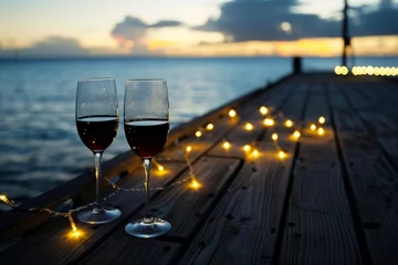 Rolgordijnen wine glasses on pier with string lights, evening mood © primopiano