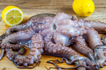Raw octopus with lemon on a wooden board. 