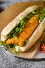 Fried fish sandwich with greens on the stone table. Turkish name Balik Ekmek