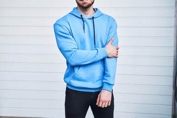 mockup shows a stylish man wearing a blue hoodie and leaning on a white wall. It is perfect for...