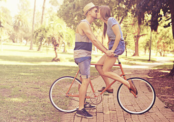 Couple, kiss and park with bike, date and relaxation for relationship bonding and love. Man, woman...