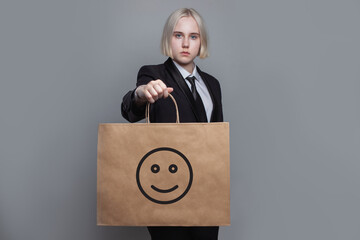 Young woman with shopping bag with icon smile emoticon on grey background - 769475152