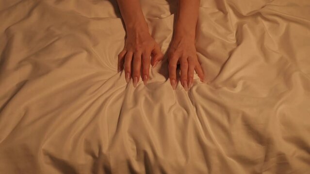 female woman girl hands in sex and orgasm grab and squeeze the white sheet on the bed
