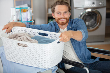 man in wheelchair lifting laundry basket on to ironing board - Powered by Adobe