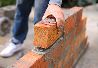 Bricklayer, hand and construction with man builder on roof, working employee in industrial industry and contractor career. Outdoor, cement on site with handyman staff, skilled masonry with bricks