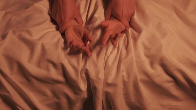 hands of girl woman and a man in hard sex and orgasm on a white sheet on the bed in close-up. Couple having sex