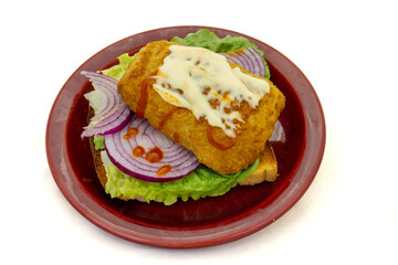 A portion of hake with mayonnaise and tabasco sauce on a slice of white bread toast with fresh lettuce and red onion as a snack