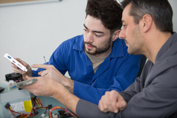 Obraz premium mechanic man with apprentice fixing a metal piece