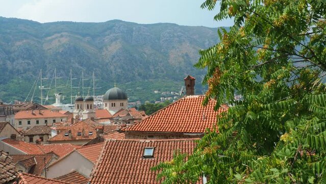 Kotor is a coastal city in Montenegro. Bay of Kotor. Red tiled roofs, mountain and chimneys of a tourist ship. Excursions and tourism. Cathedral of Saint Tryphon. Medieval old towns in the Adriatic
