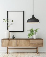 A simple modern room with white walls, a sideboard and hanging lamp in the background. A black thin frame hangs on wall above cabinet