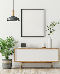 A simple modern room with white walls, a sideboard and hanging lamp in the background. A black thin frame hangs on wall above cabinet