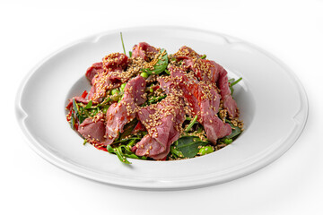 Hearty salad. Thinly sliced beef pastrami with greens on a white plate. Banquet festive dishes. Gourmet restaurant menu. White background.