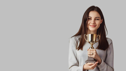 Beautiful woman holding a trophy. Smiling and beautiful woman showing achievement and success with copy space background
