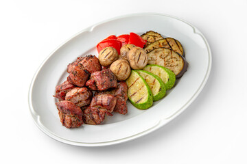 Shish kebab meat with grilled vegetables on a white plate. Banquet festive dishes. Gourmet restaurant menu. White background.