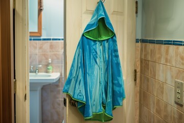 kids blue and green hooded poncho hanging on a bathroom door