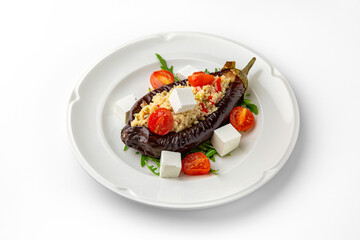 Vegetarian dish. Baked eggplant stuffed with bulgur, or rice with bryndza and vegetables on a white plate. Banquet festive dishes. Gourmet restaurant menu. White background.
