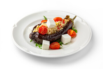 Vegetarian dish. Baked eggplant stuffed with bulgur, or rice with bryndza and vegetables on a white plate. Banquet festive dishes. Gourmet restaurant menu. White background.