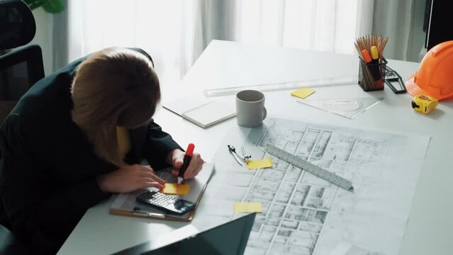 Top view of smart civil engineer drawing and measuring blueprint by using ruler. Aerial view of architect scatch building project plan at meeting table with equipment and safety helmet. Alimentation.