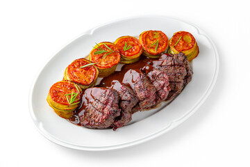 Beef tenderloin meat with ratatouille of zucchini circles, eggplant, tomato on a white plate....