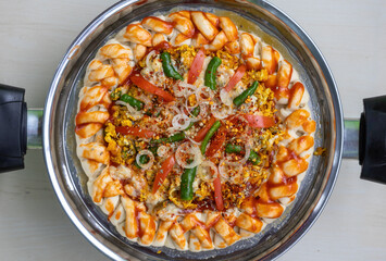 Delicious uncooked pizza in a nonstick pan. It is a healthy egg pizza with tomatoes, chili flakes, onion, green chilies, white sauce, and oregano powder. Top view of homemade raw food.