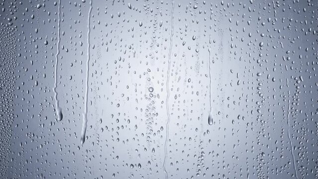 water drops following down the surface of glass. Drops of Rain trickling down.