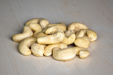 Fototapeta na wymiar Pile of cashew nuts isolated on a wooden background. In the Bengali language, it is called Kaju Badam. Cashew nuts are high in fiber, heart-healthy fats, and plant protein.