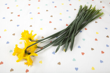 a bouquet of daffodils placed on a tablecloth patterned with multiple colored hearts