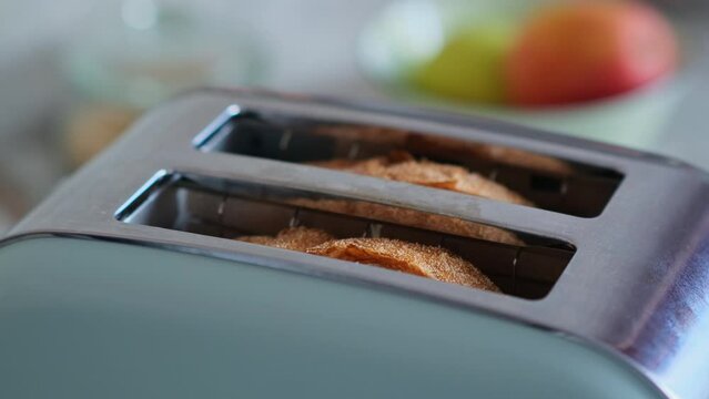 Fried wheat bread pops out of a modern toaster, close-up. Popular kitchen appliance for making a healthy breakfast.