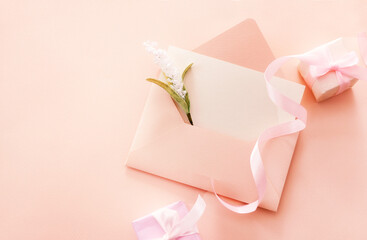 Greeting card with an open envelope and a flower and two gift boxes with pink ribbon with space. Spring vacation, gift, Valentines Day, Mothers Day, Fathers Day. Top view.