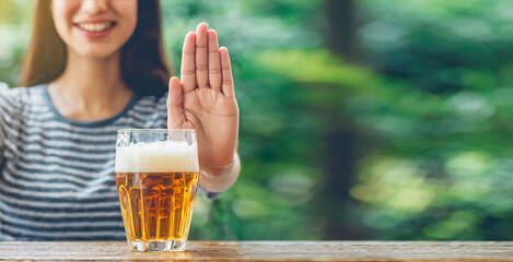 The woman refuses alcohol by making a stop sign for the beer with her hand. Concept of drunk driving, alcoholism and harms of alcohol