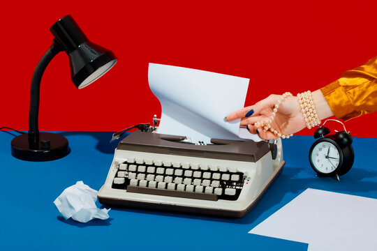 Writer removing paper from typewriter on desk