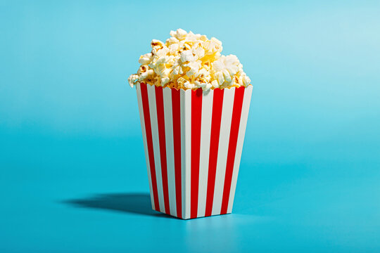 Popcorn in striped container over blue background