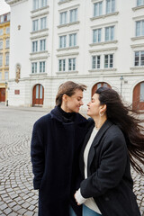 Intimate moment of cheerful lgbt couple in love standing together on street in European city