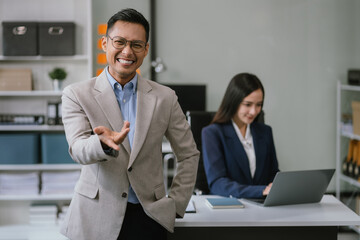 Happy young Asian male presenting or showing open hand palm, happy working.