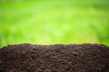 ground heap on a green background. black soil with blurred green grass